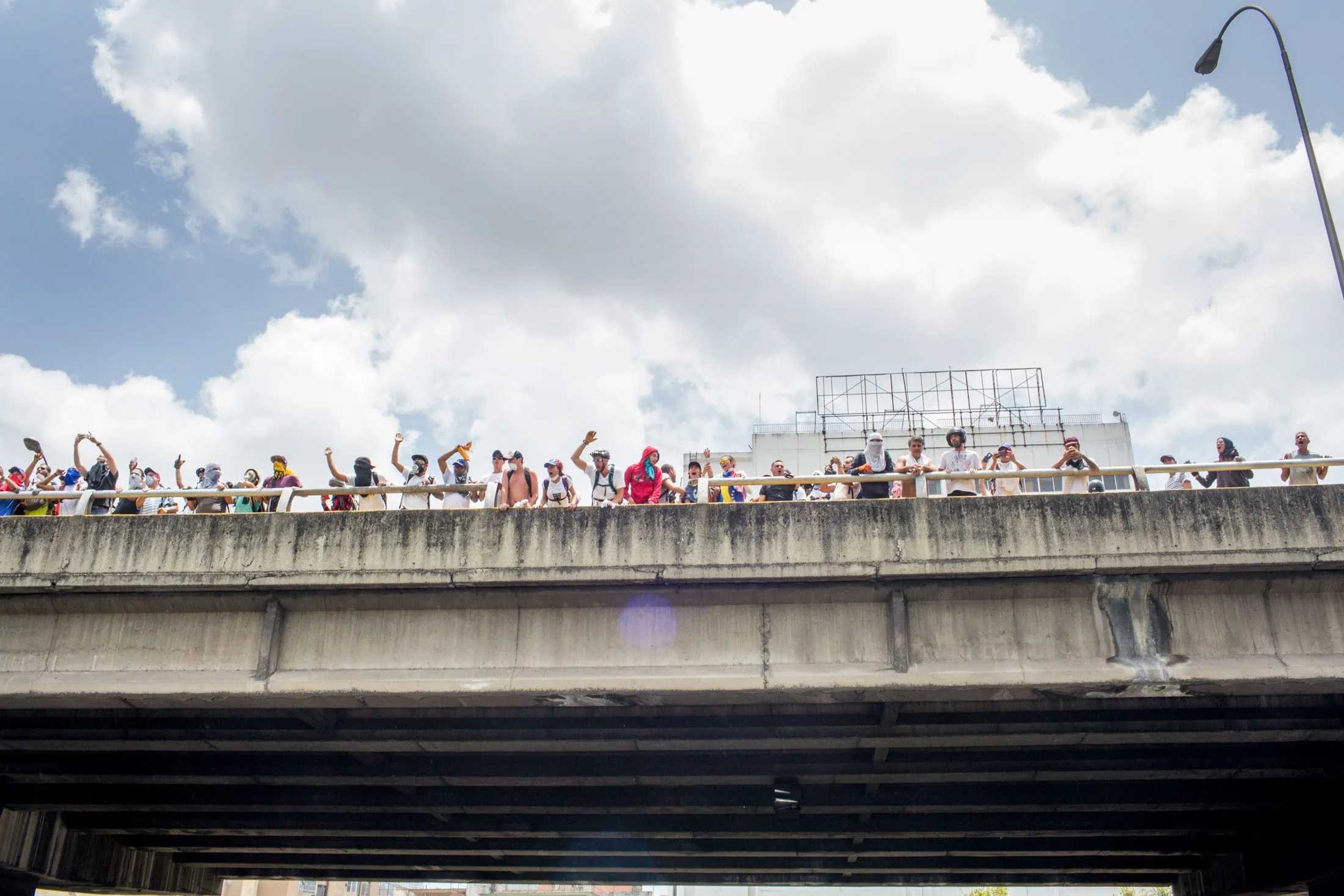 Protesters cheer on the clashes from a highway overpass in Caracas.
