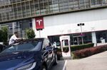 A man cleans a Tesla Inc. Model X electric vehicle connected to a charging station outside one of the company's showrooms in Beijing, China.