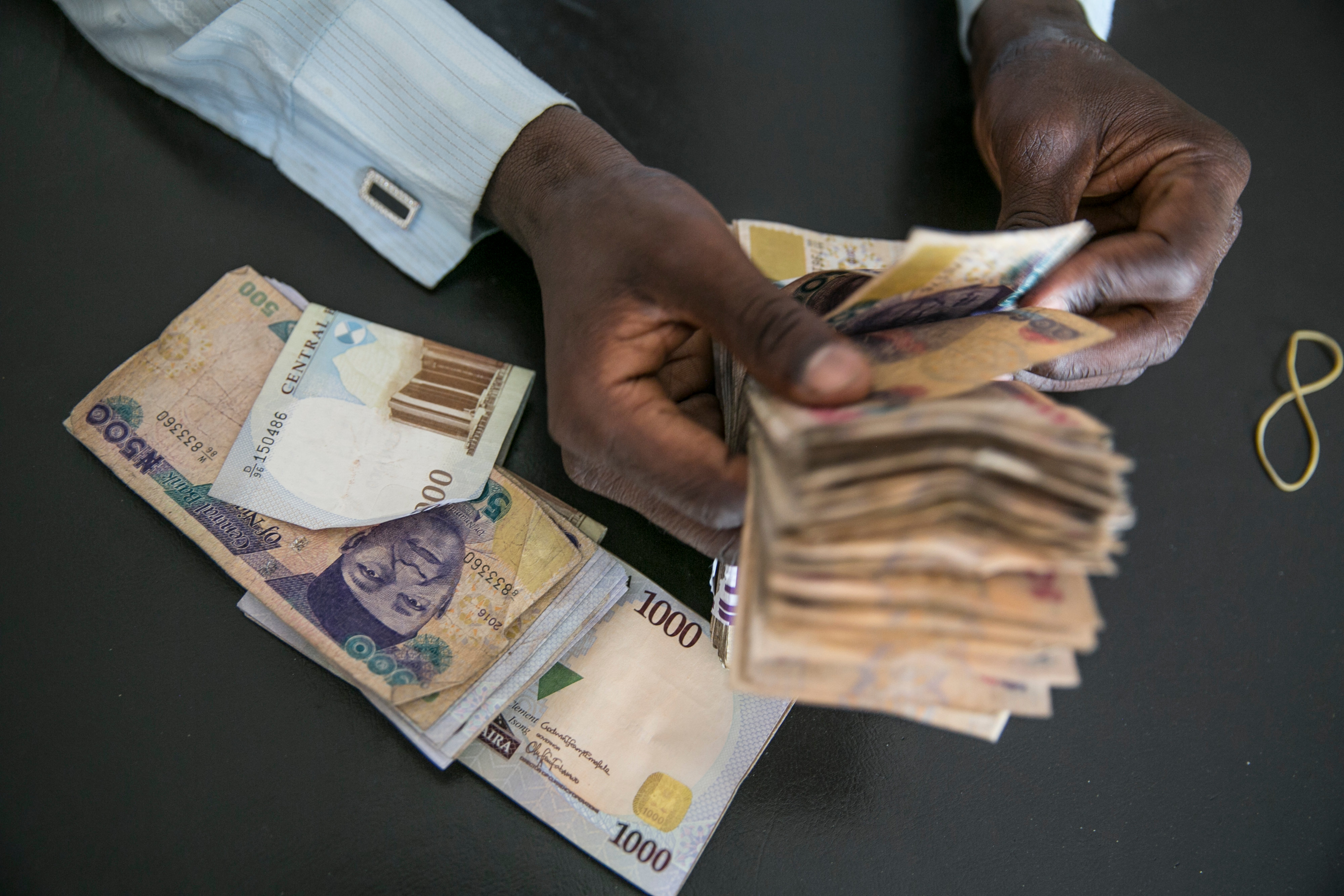A clerk at a currency exchange bureau counts Nigerian naira banknotes.&nbsp;