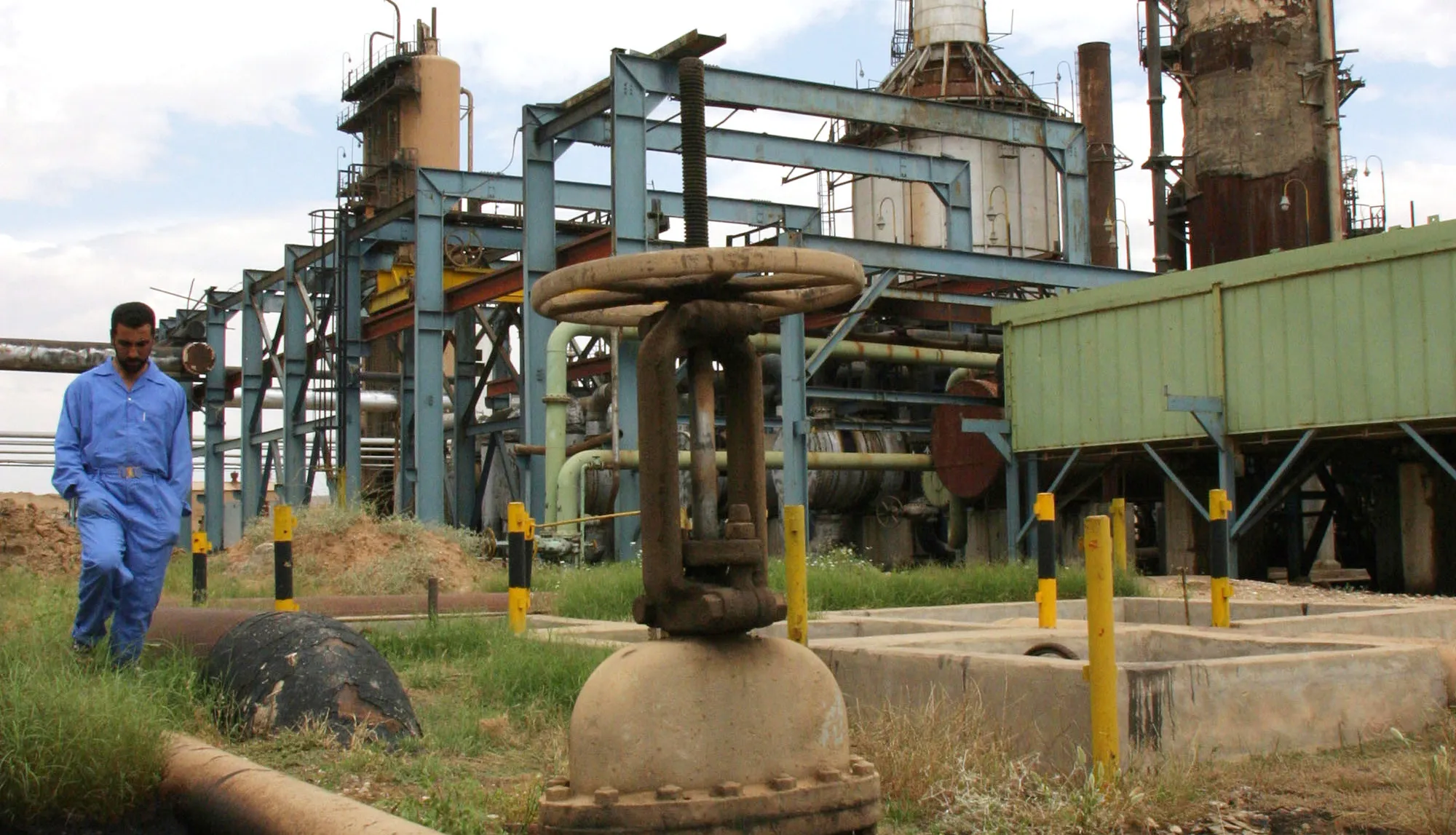 A worker walks between pipes at the oil and gas separation facility at the Baba Gurgur oil field in the Arafa district of Kirkuk, northern Iraq, on May 13, 2004.
