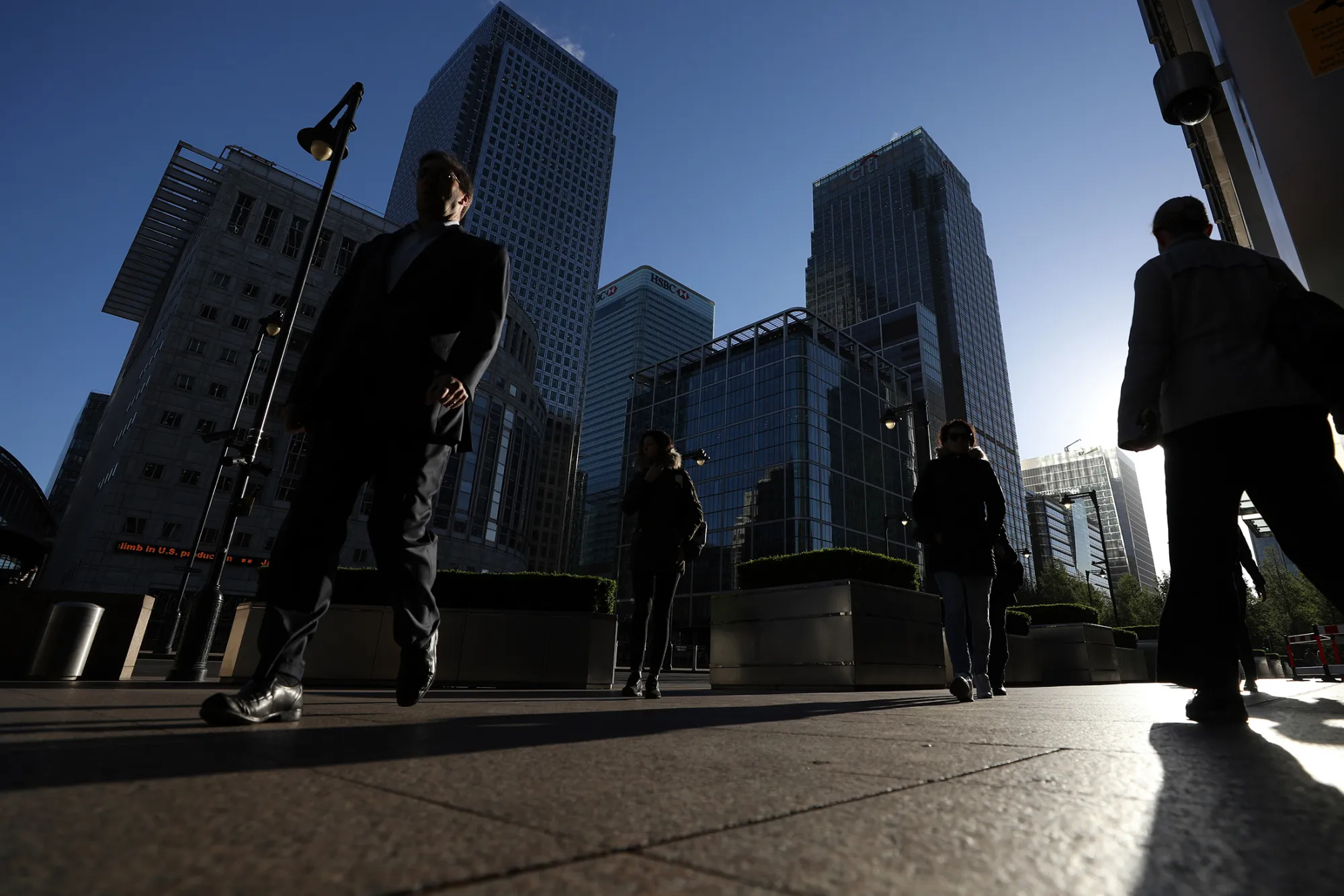 Pedestrians pass in front of the offices of global financial institutions, including Citigroup Inc., HSBC Holdings Plc and the commercial office block No. 1 Canada Square, in the Canary Wharf financial, shopping and business district in London on April 18, 2017.
