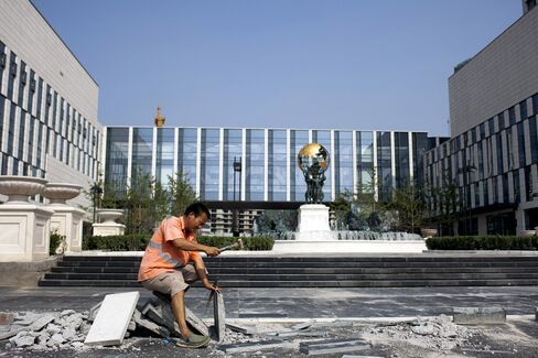 A worker puts finishing touches to a building which has a globe statue, similiar to the Atlas statue at New York, at the Tianjin Binhai New Area CBD of Tianjin, China, in 2011.