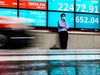A man wearing a face mask stands in front of an electric quotation board displaying the numbers of the Nikkei 225 Index on the Tokyo Stock Exchange in Tokyo on June 11, 2020.