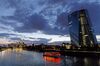 A sightseeing boat travels on the River Main past the European Central Bank (ECB) skyscraper headquarters, right, at dusk in Frankfurt, Germany.