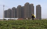 A farmer walks past a field near new residential buildings in Jianxing, about 60 miles from Shanghai.
