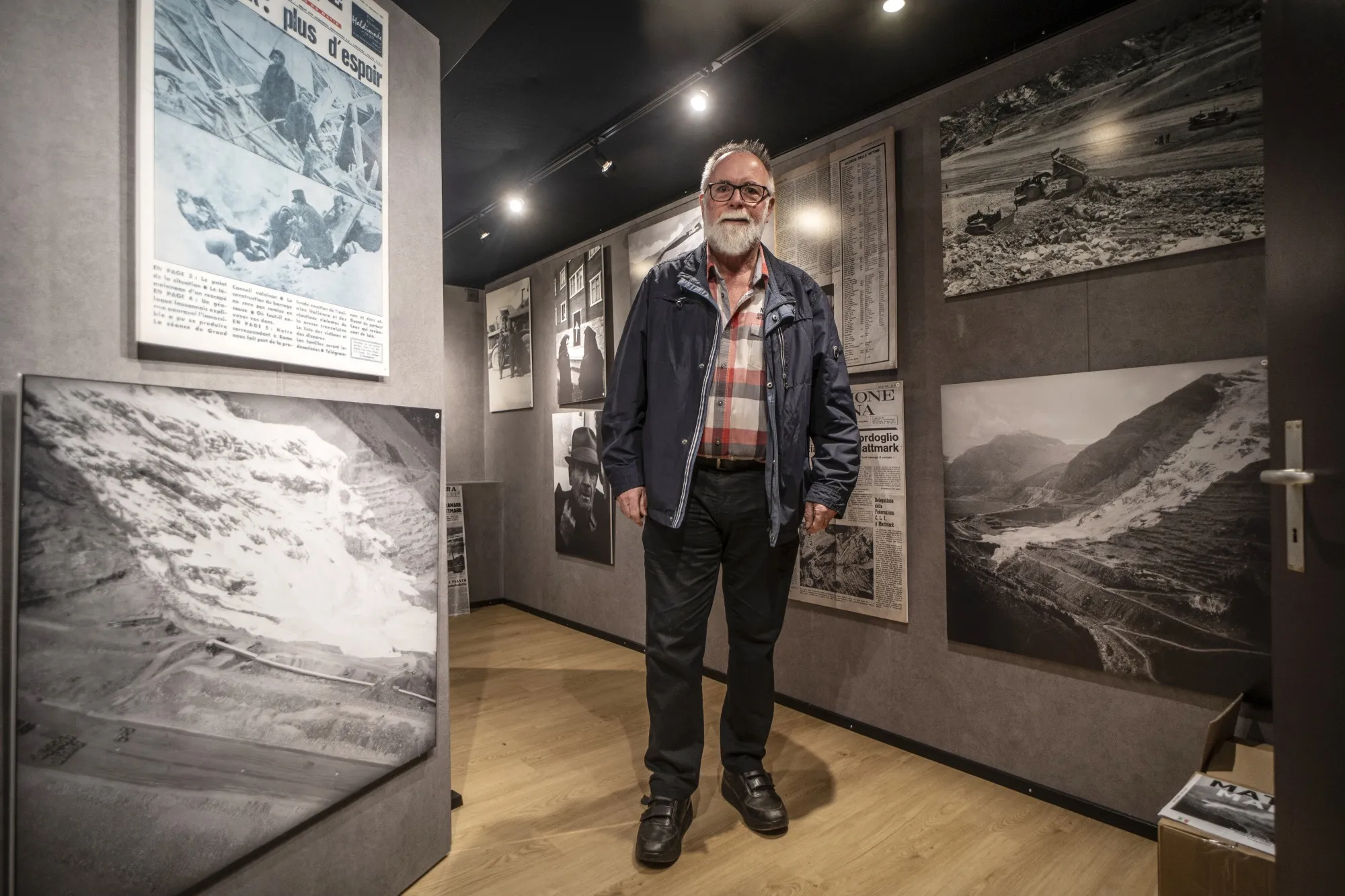 Christoph Gysel poses for a photo in a hallway of a museum exhibit with large photos showing collapses of other glaciers.