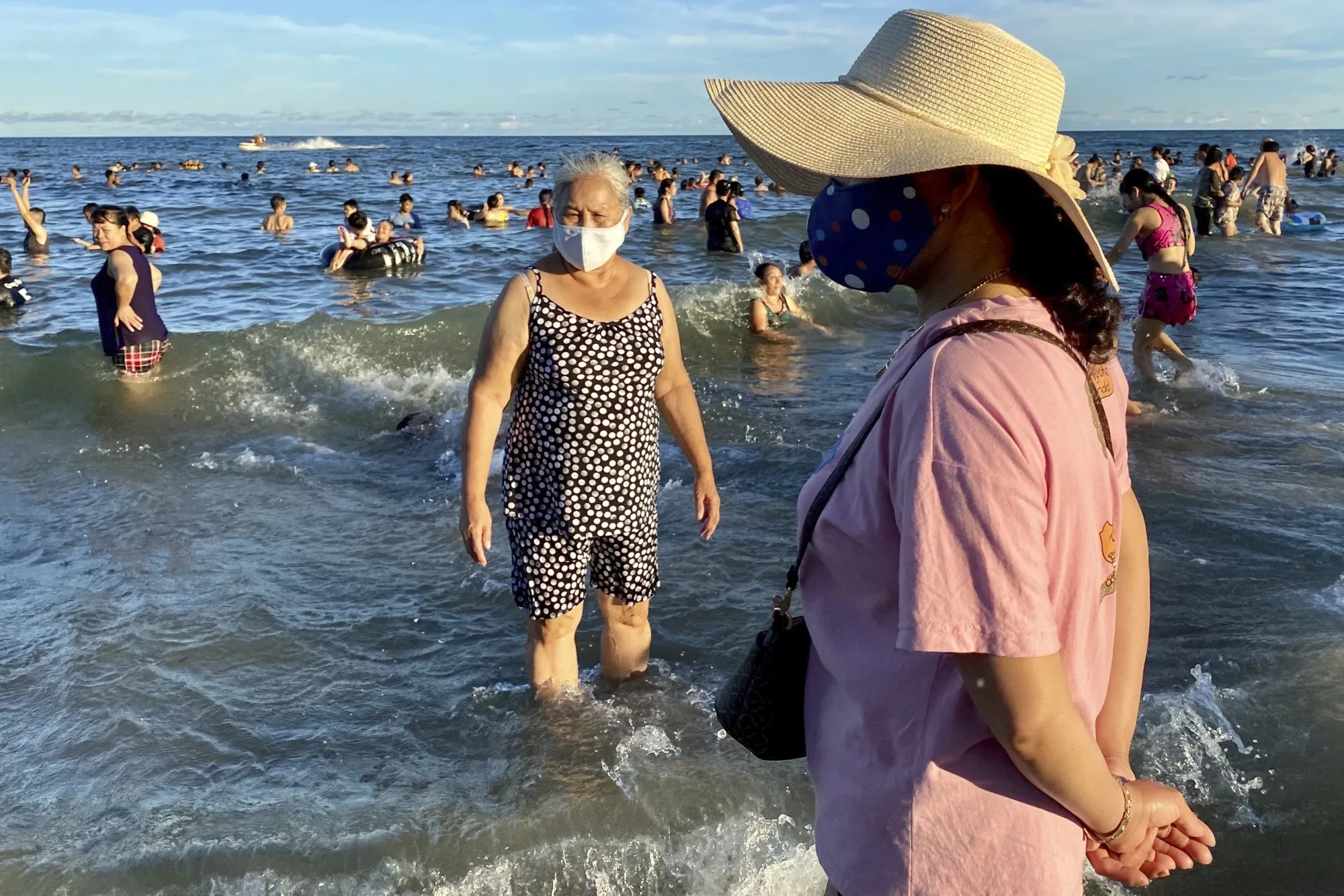 Women wearing face masks stand on a beach in Vung Tau, Vietnam, July 26.