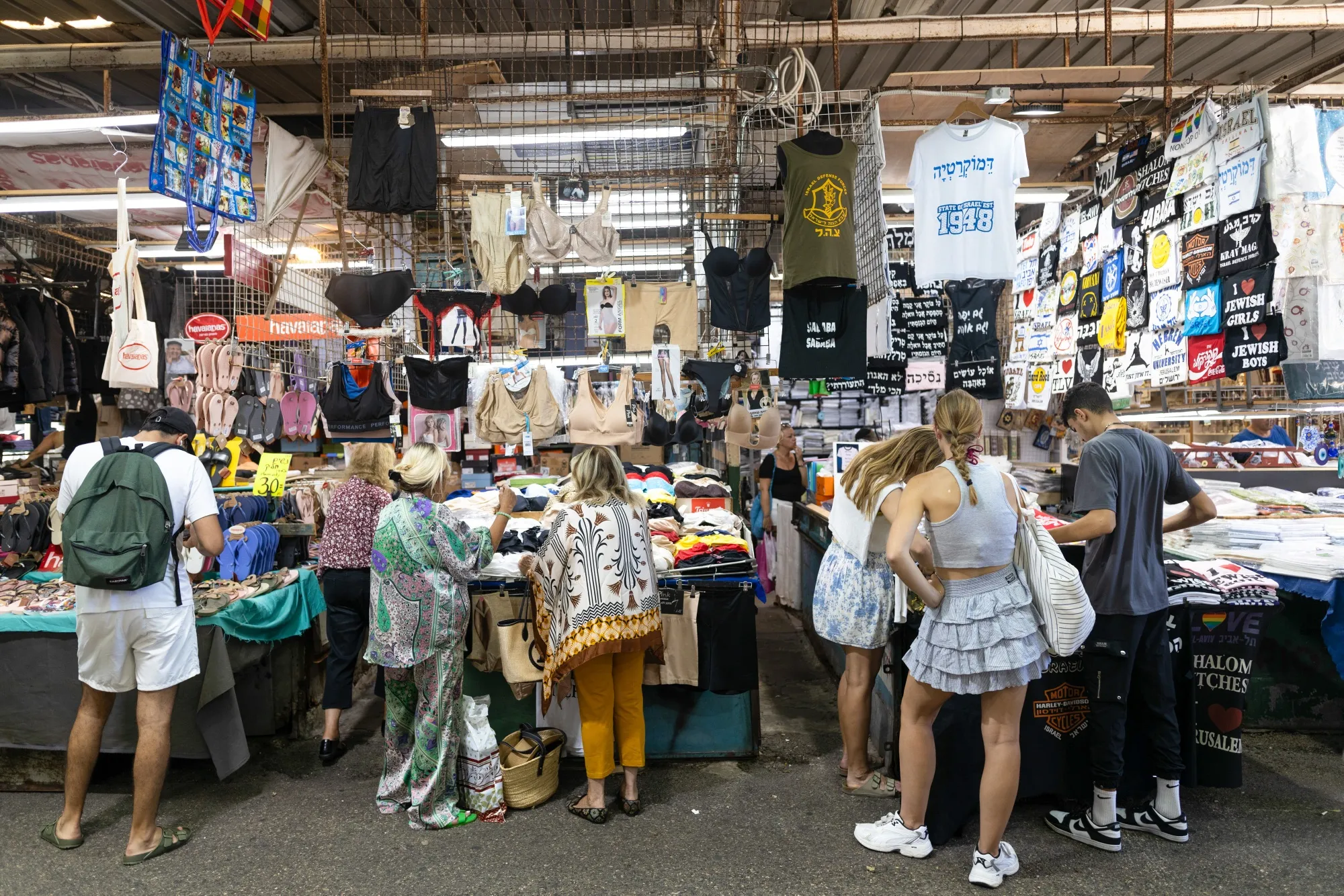 Shoppers browse garments at a clothing stall at Carmel Market in Tel Aviv.