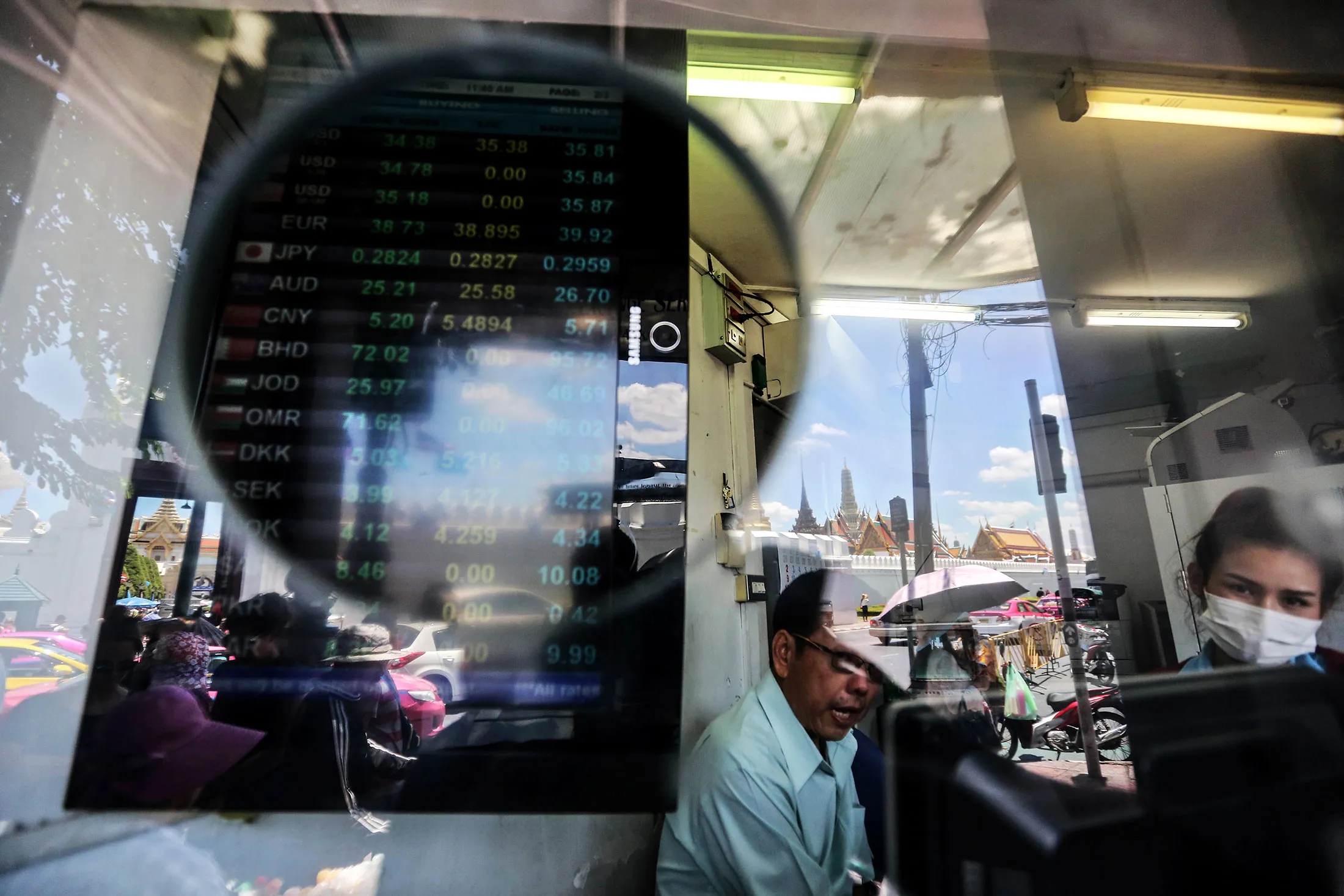 Tourists and the Grand Palace are reflected in the window as exchange rates are displayed on a board at a bank in Bangkok. “Developments surrounding the slower growth in emerging-market economies are posing renewed risks to the euro-area outlook,” Draghi said on Friday.
