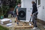 Workers install a heat pump unit at a 1930s-built house in Folkestone, UK, in 2021.