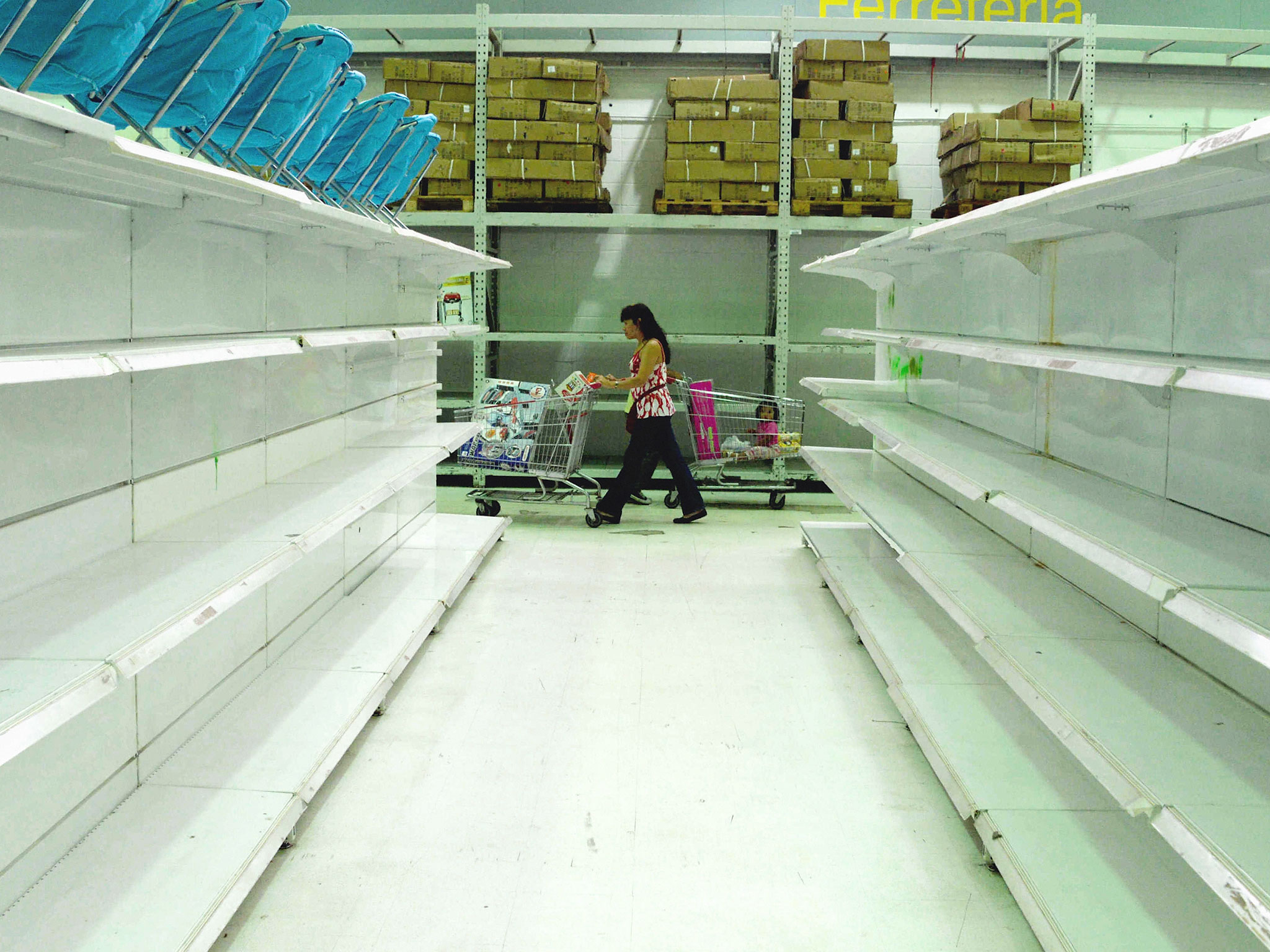 A consumer walks around empty shelves due to the lack of foreign currency cause lack of imported stuffs at a state-run super market on December 18, 2014 in Caracas, Venezuela.
