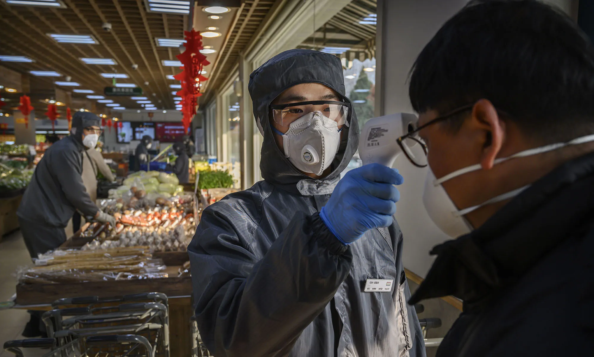A worker checks the temperature of a customer at a supermarket in Beijing on Feb. 11.