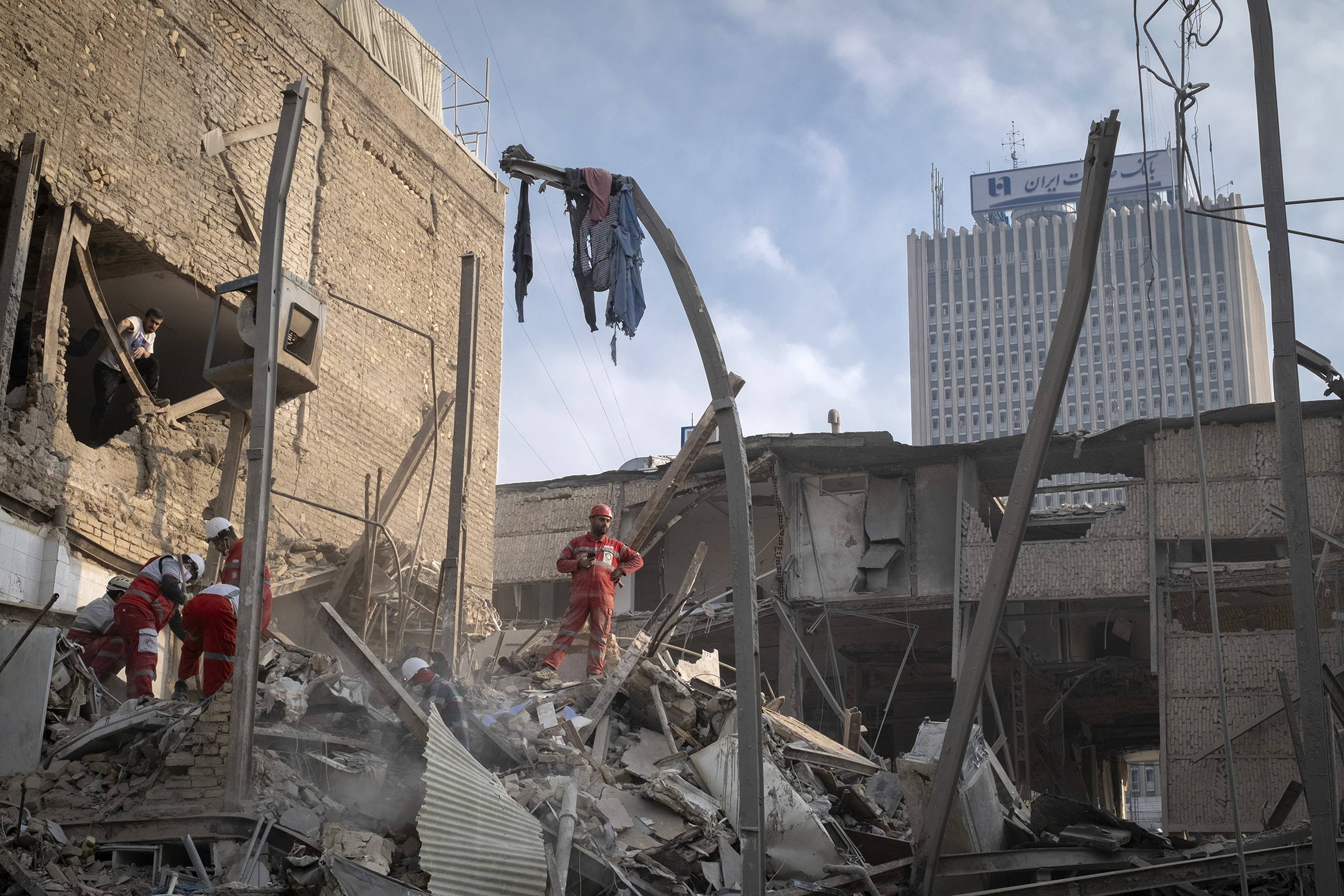 A rescue member of the Iranian Red Crescent Society (IRCS) stands on the ruins of a building in a residential area in Tehran, Iran, on March 16, 2026. The building was destroyed during a U.S.-Israeli military operation. (Photo by Morteza Nikoubazl/NurPhoto via Getty Images) Photographer: NurPhoto/NurPhoto