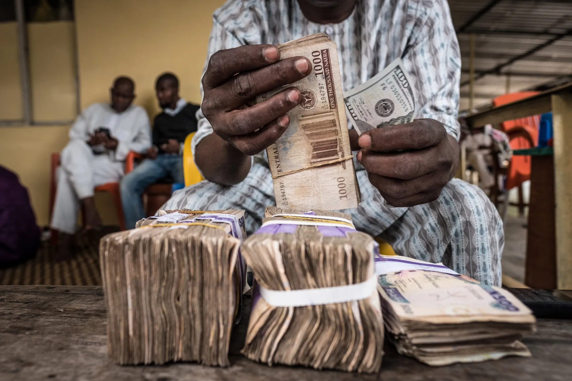 A currency dealer counts bundles of naira banknotes