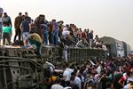 People climb an overturned train carriage as they gather at the scene of a railway accident in Toukh, Egypt, on April 18.