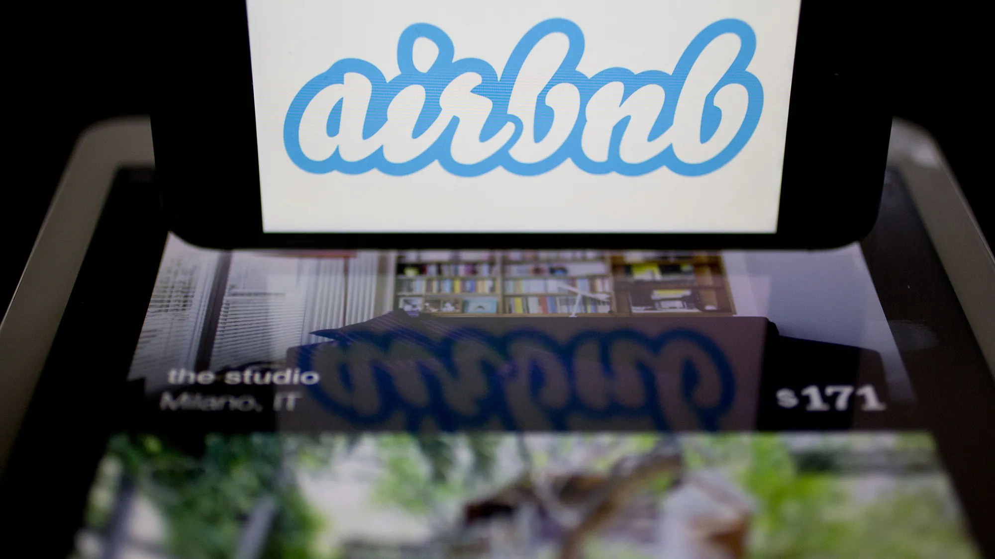 The Airbnb Inc. logo and application are displayed on an Apple Inc. iPhone and iPad in this arranged photograph in Washington, D.C., U.S., on Friday, March 21, 2014. Airbnb Inc. is raising money from investors including TPG Capital in a financing round that would value the room-sharing service at more than $10 billion, said people with knowledge of the deal.
