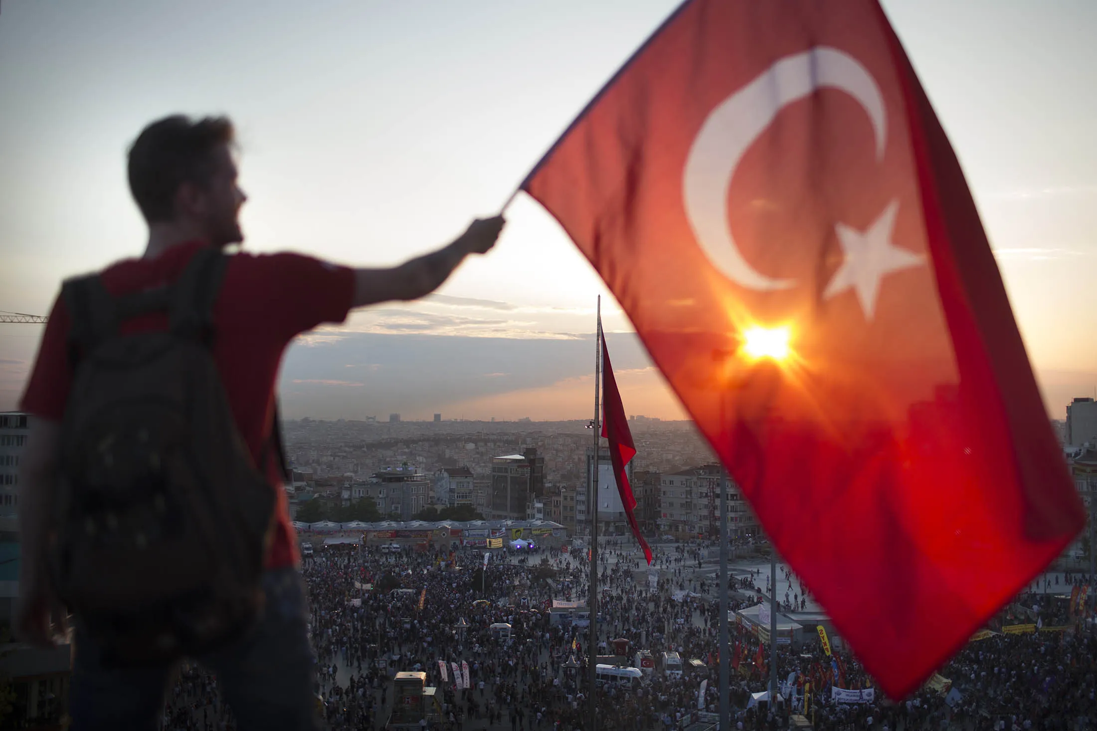 A man waves the Turkish flag from a roof top at Taksim square in Istanbul.
