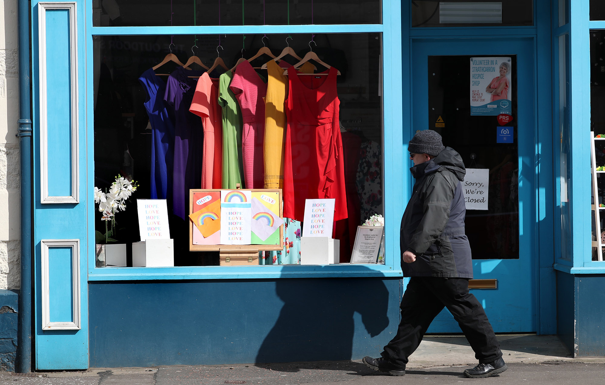 A man walks past a closed charity shop during lockdown in Callander, U.K.