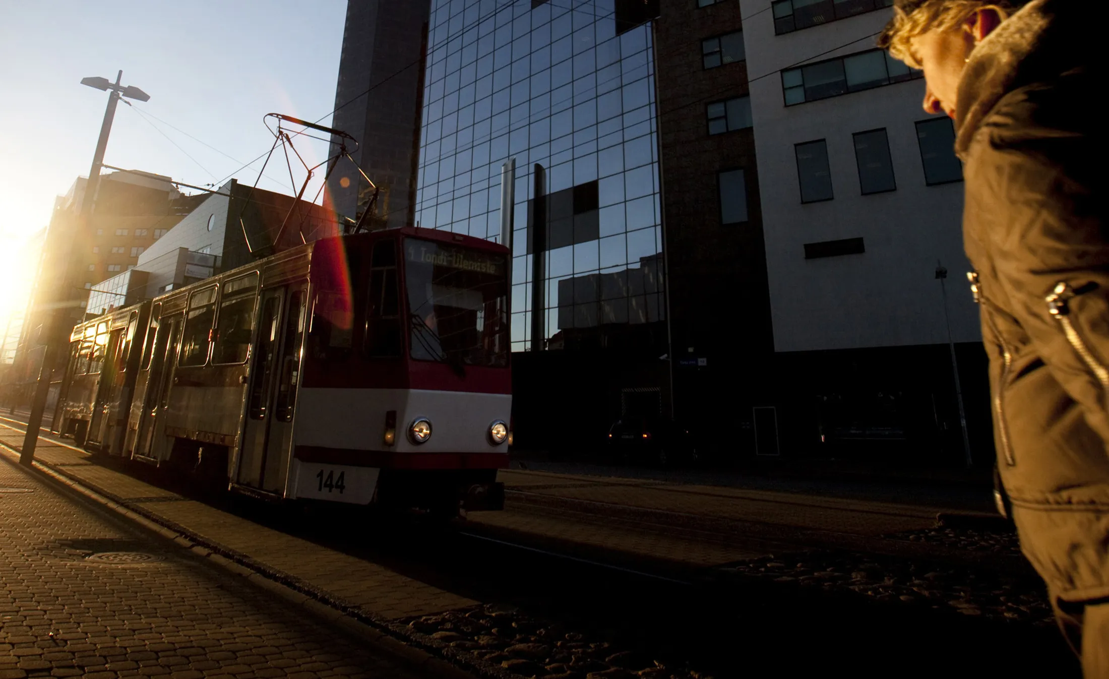 A pedestrian passes a tram in the business district of Tallinn, Estonia.