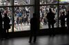 People are silhouetted as they stand on a footbridge overlooking pedestrians crossing an intersection in the Shibuya district of Tokyo.