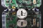 A coin representing Litecoin cryptocurrency sits reflected on a polished surface and photographed against a computer circuit board in this arranged photograph in London, U.K., on Thursday, Feb. 8, 2018. Cryptocurrencies tracked by Coinmarketcap.com have lost more than $500 billion of market value since early January as governments clamped down, credit-card issuers halted purchases and investors grew increasingly concerned that last year’s meteoric rise in digital assets was unjustified.