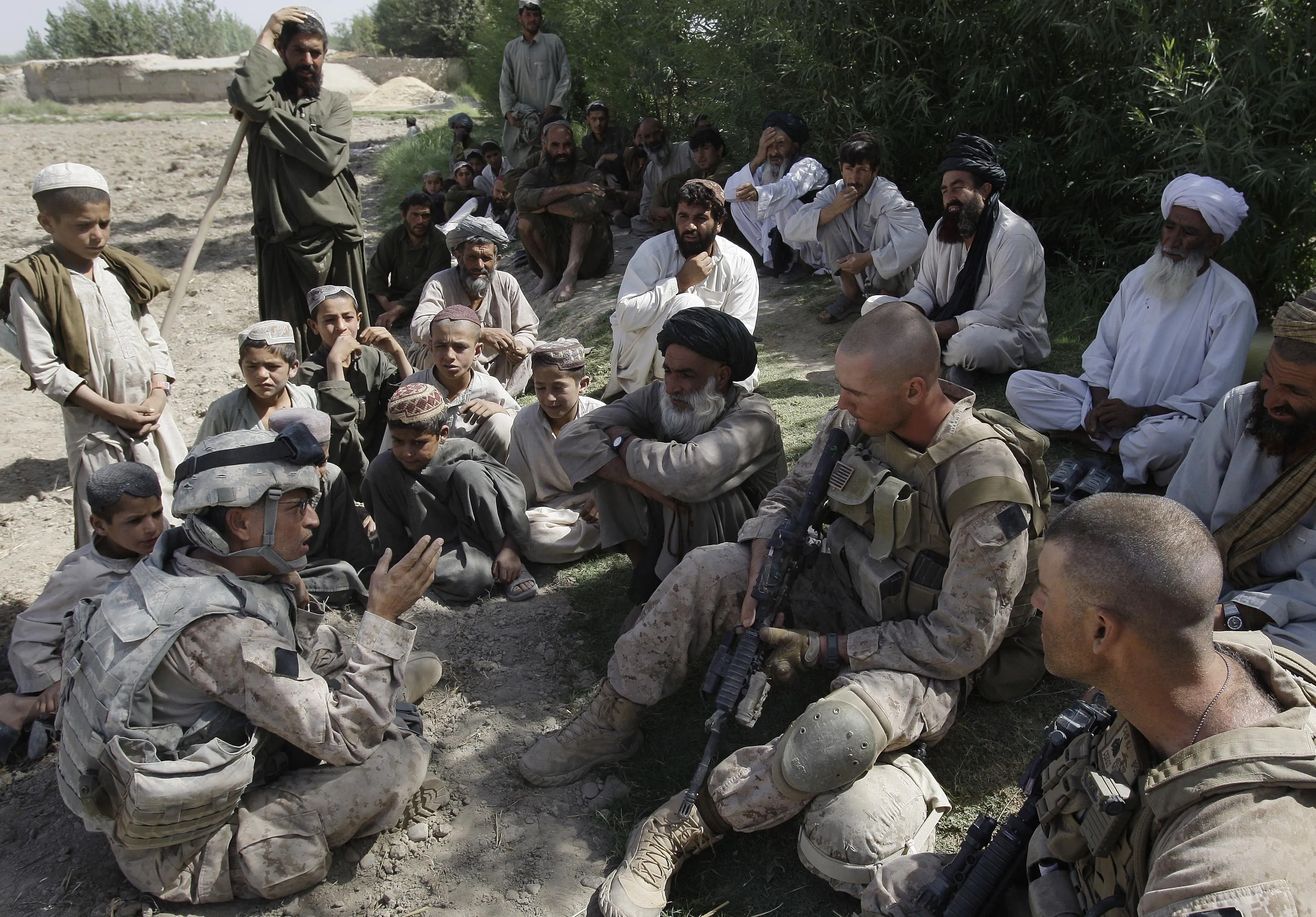 A translator for the U.S. Marines, left, speaks with villagers in Helmand province, Afghanistan in 2009.