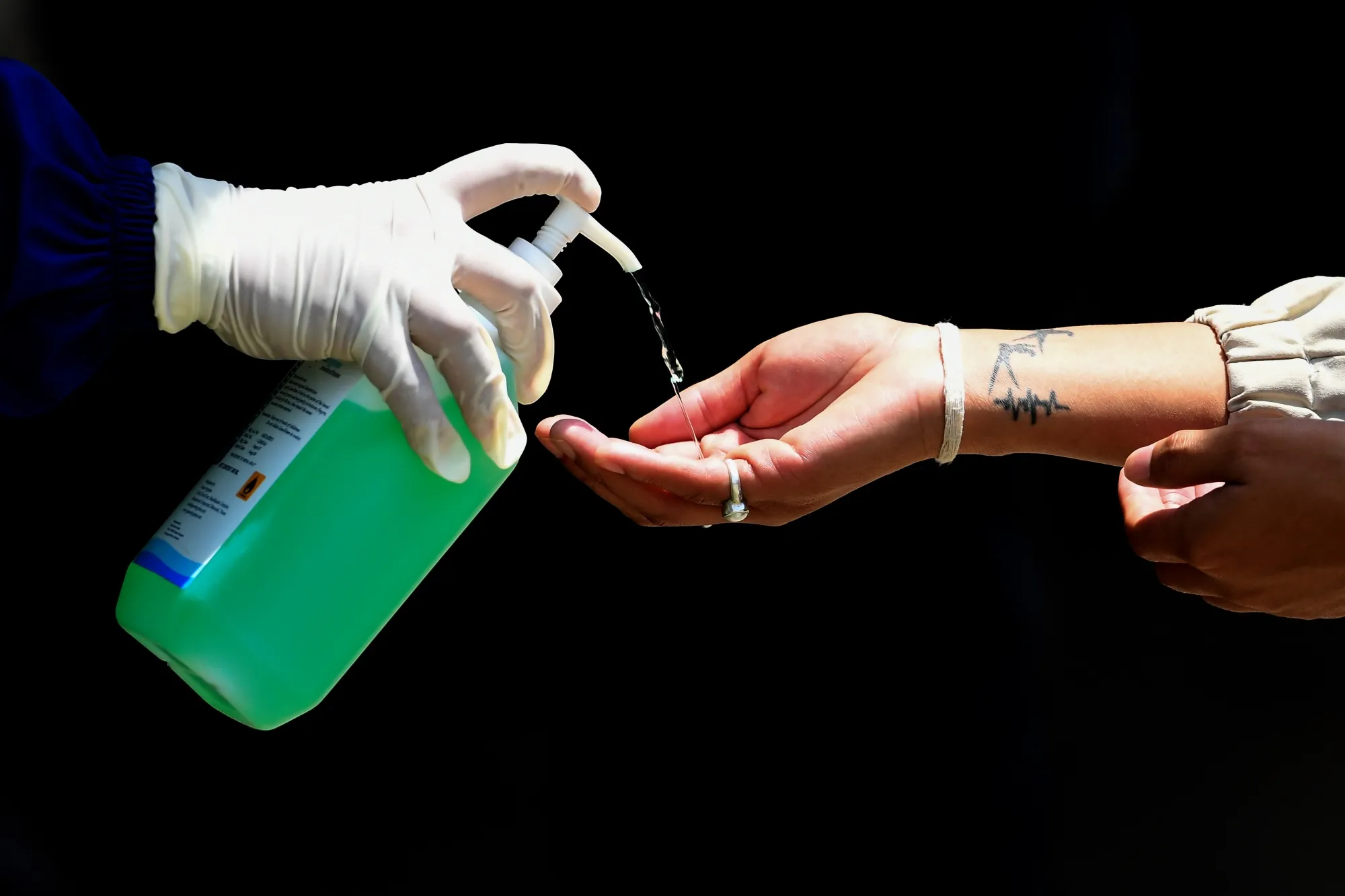 A health worker dispenses sanitizer to a person.