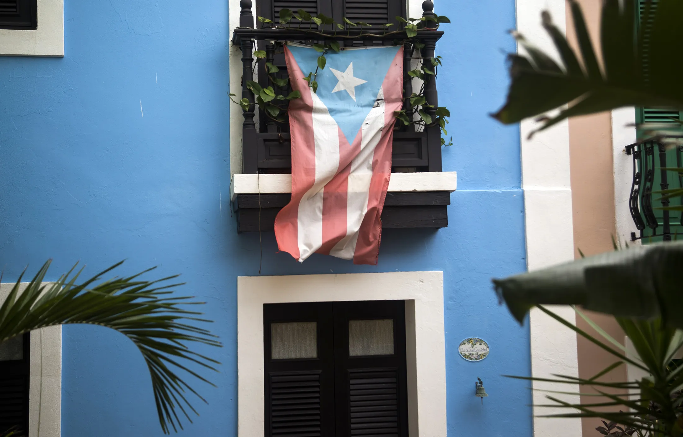 A Puerto Rican flag hangs from the balcony of a house in San Juan.
