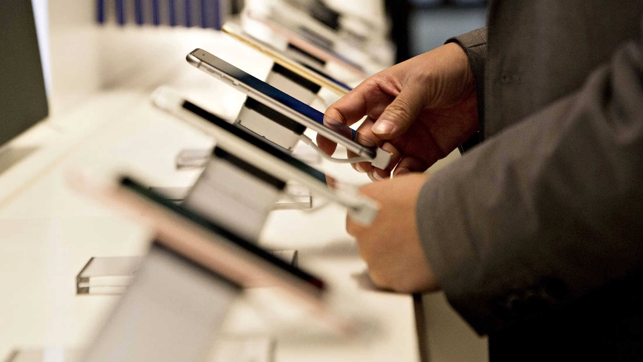 A shopper looks over a display of Apple Inc. iPhones at a T-Mobile US Inc. store in Chicago, Illinois, U.S., on Friday, Oct. 21, 2016. T-Mobile US Inc. is scheduled to release earnings figures on October 24.