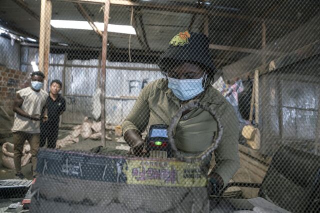 A woman measures the grade of copper and cobalt at the purchasing counter of a Chinese-run depot in Musompo outside Kolwezi.