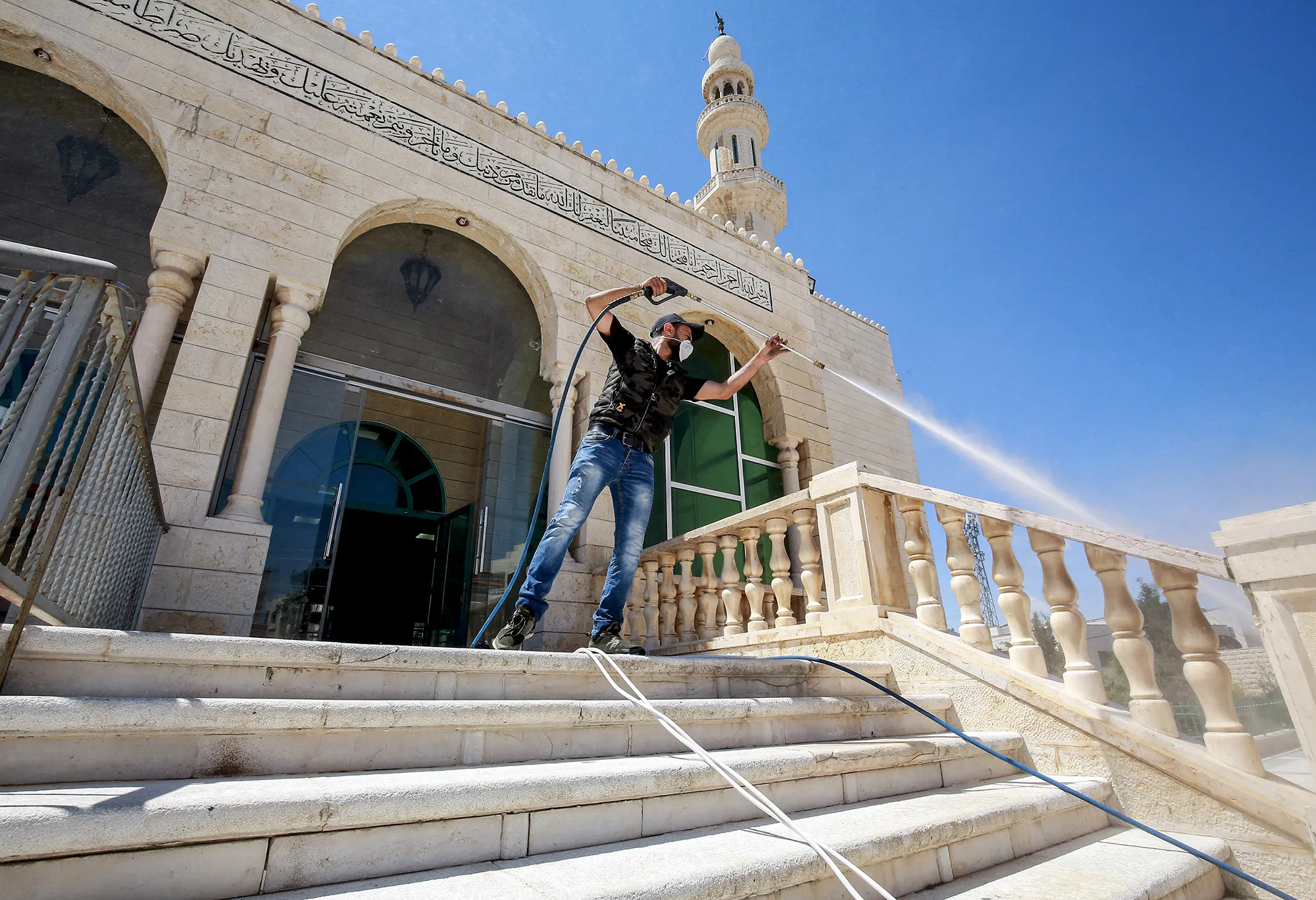 A worker sterilizes steps leading to the entrance of a mosque in&nbsp;Amman on June 3.