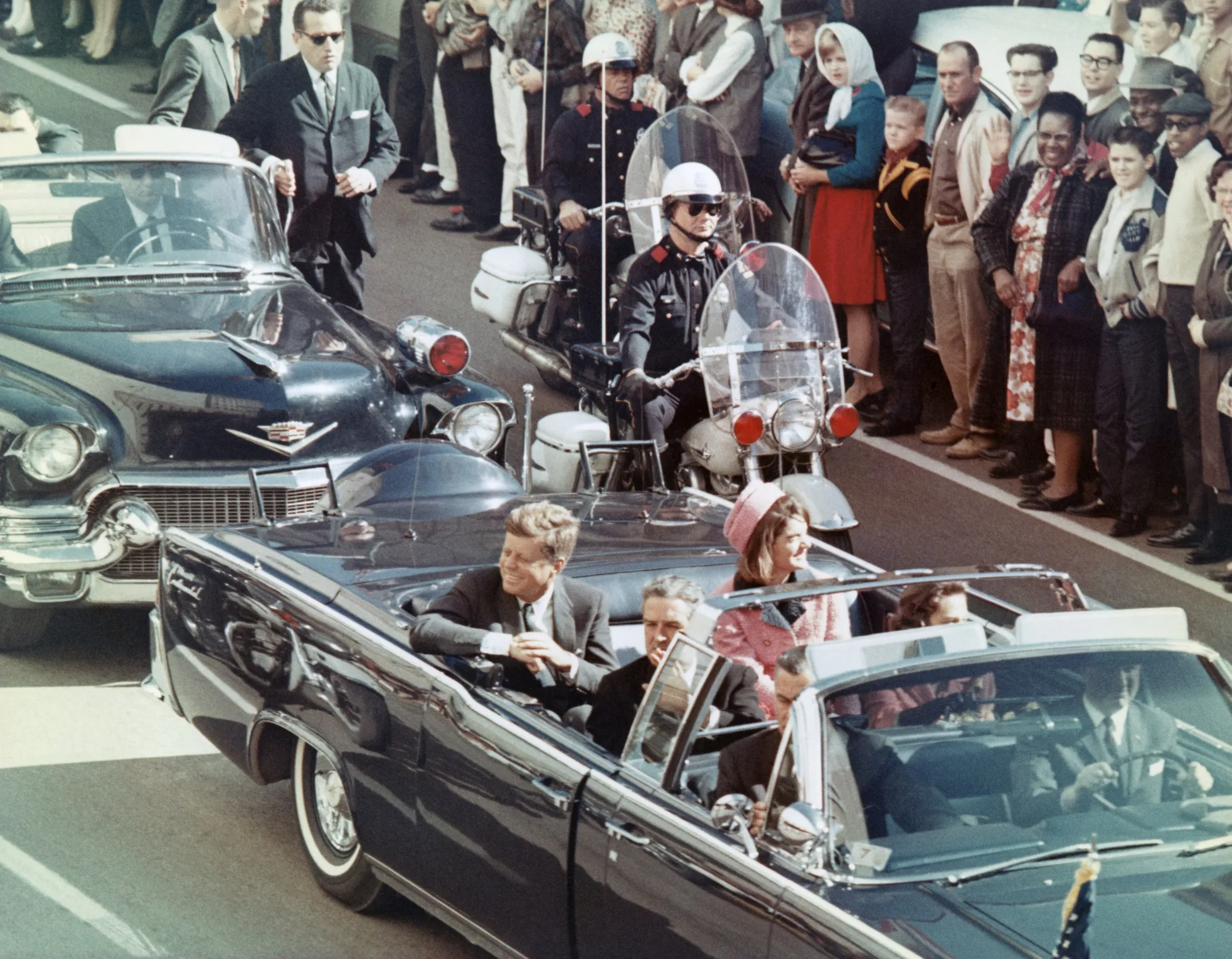 John F Kennedy smiles at the crowds lining their motorcade route in Dallas on Nov. 22, 1963.