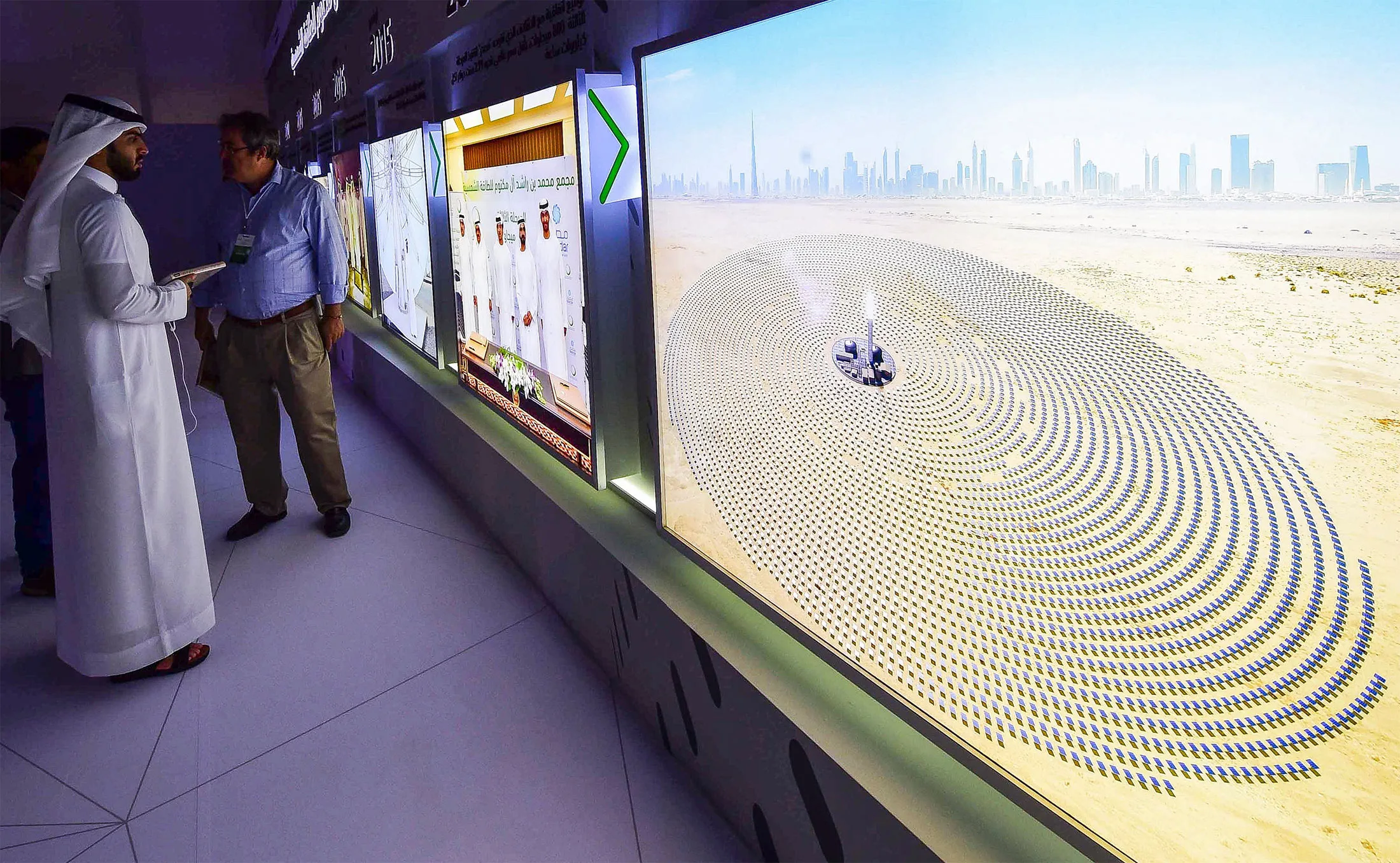 Visitors look at screens displaying images of the Mohammed bin Rashid Al-Maktoum Solar Park on March 20, 2017, at the solar plant in Dubai.
