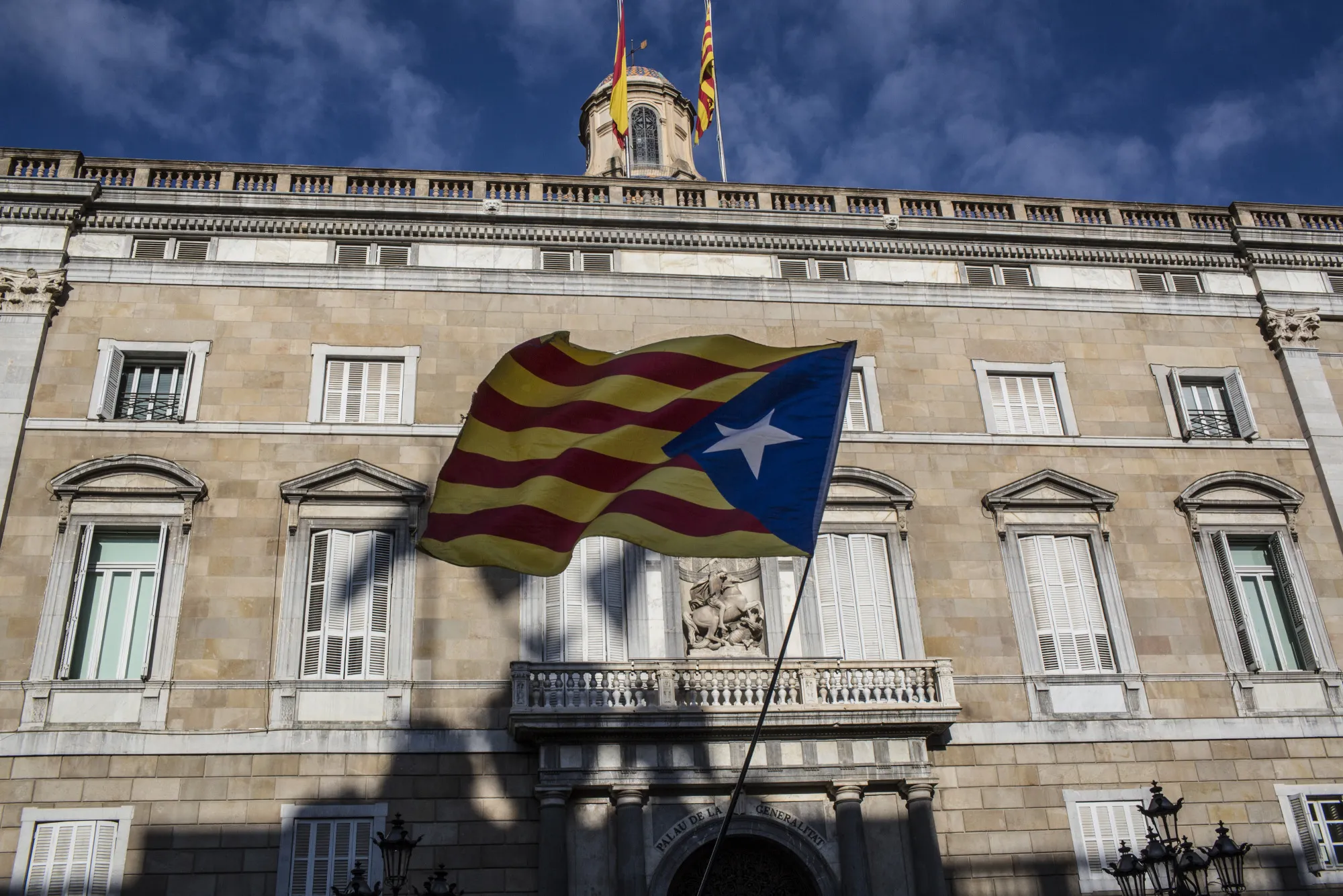 A Catalan independence supporter flies a Catalan Estelada flag outside the regional government offices in Barcelona.