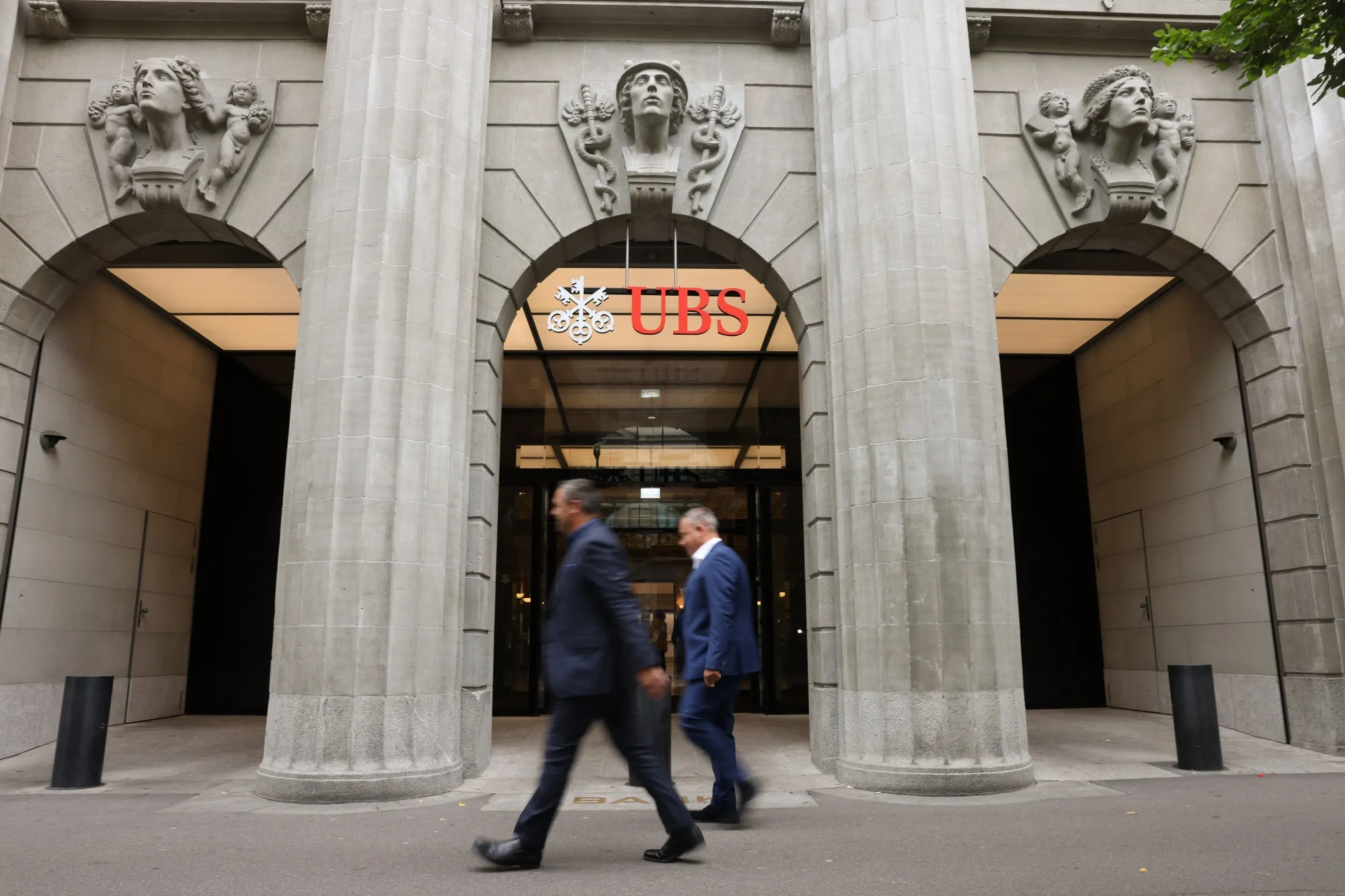 Office workers pass the UBS Group AG headquarters in Zurich, Switzerland.