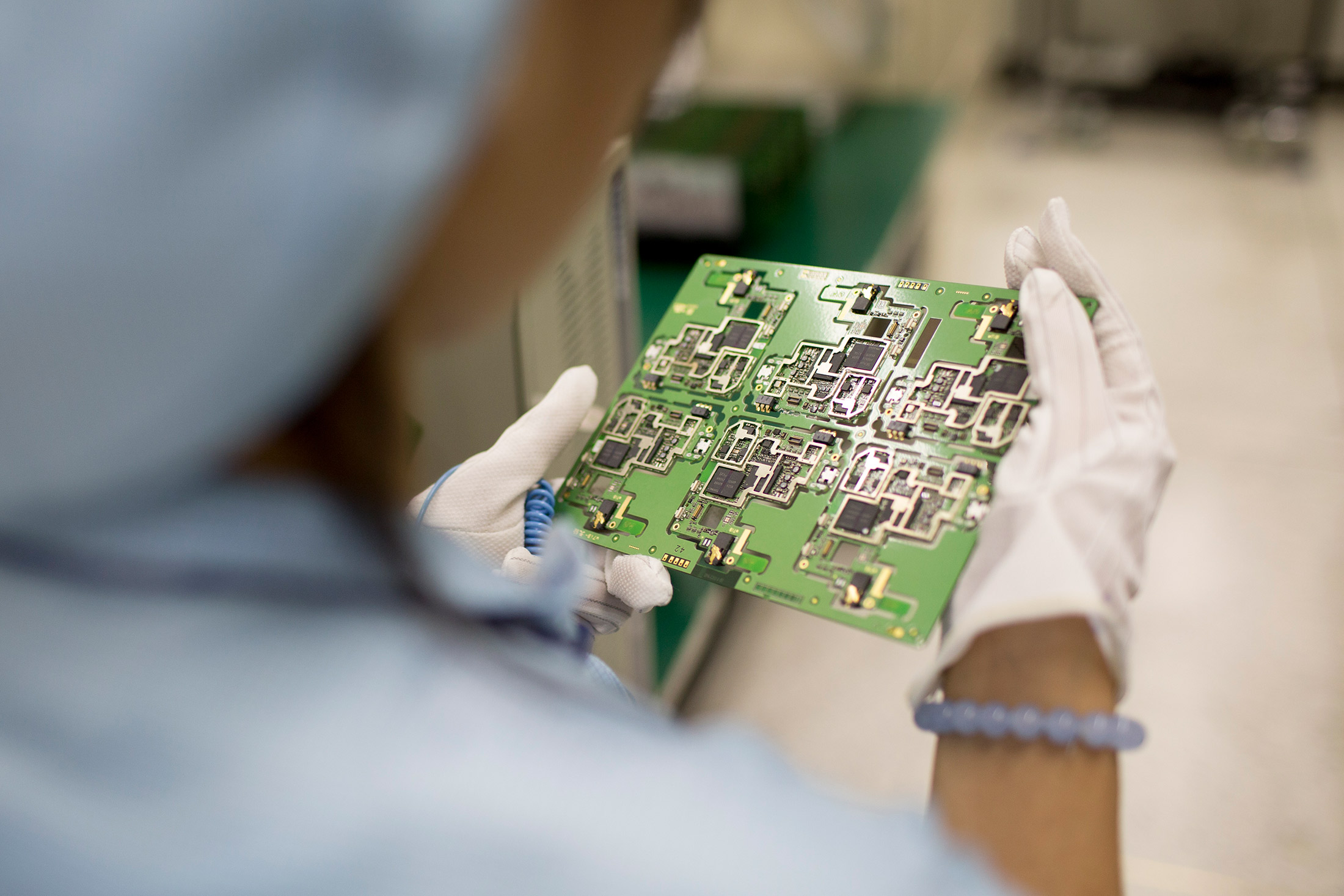 A worker inspects smartphone circuit boards at a ZTE manufacturing facility in Shenzhen, China.
