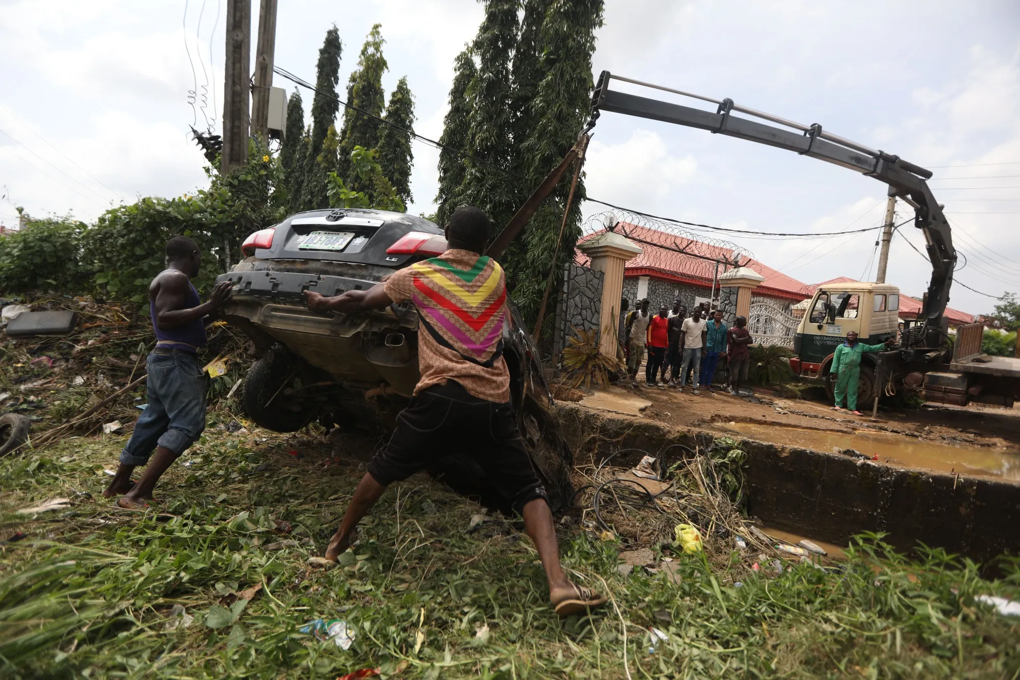 People attempt to remove a car washed away by flood water in Abuja, Nigeria.&nbsp;