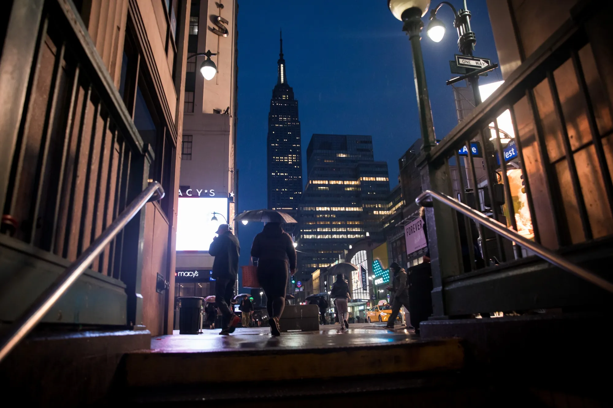 Pedestrians carrying umbrellas pass in front of the Empire State Building in New York.