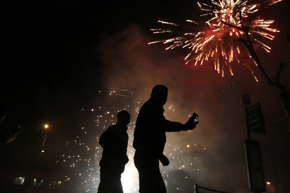 A man takes a picture on his phone as fireworks are set off in Shanghai during Chinese New Year in 2015.