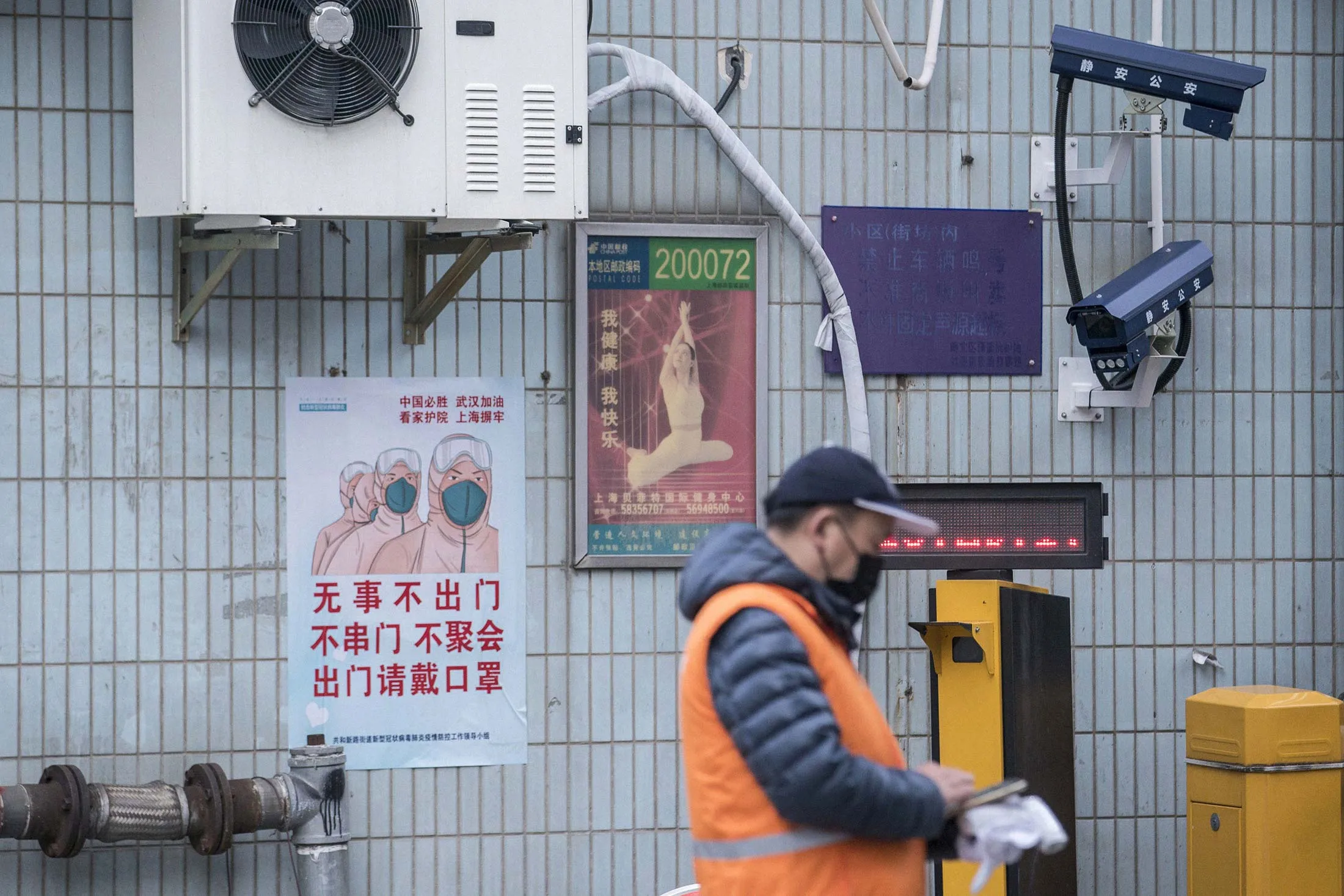 A poster featuring people wearing protective masks is displayed near surveillance cameras in Shanghai.