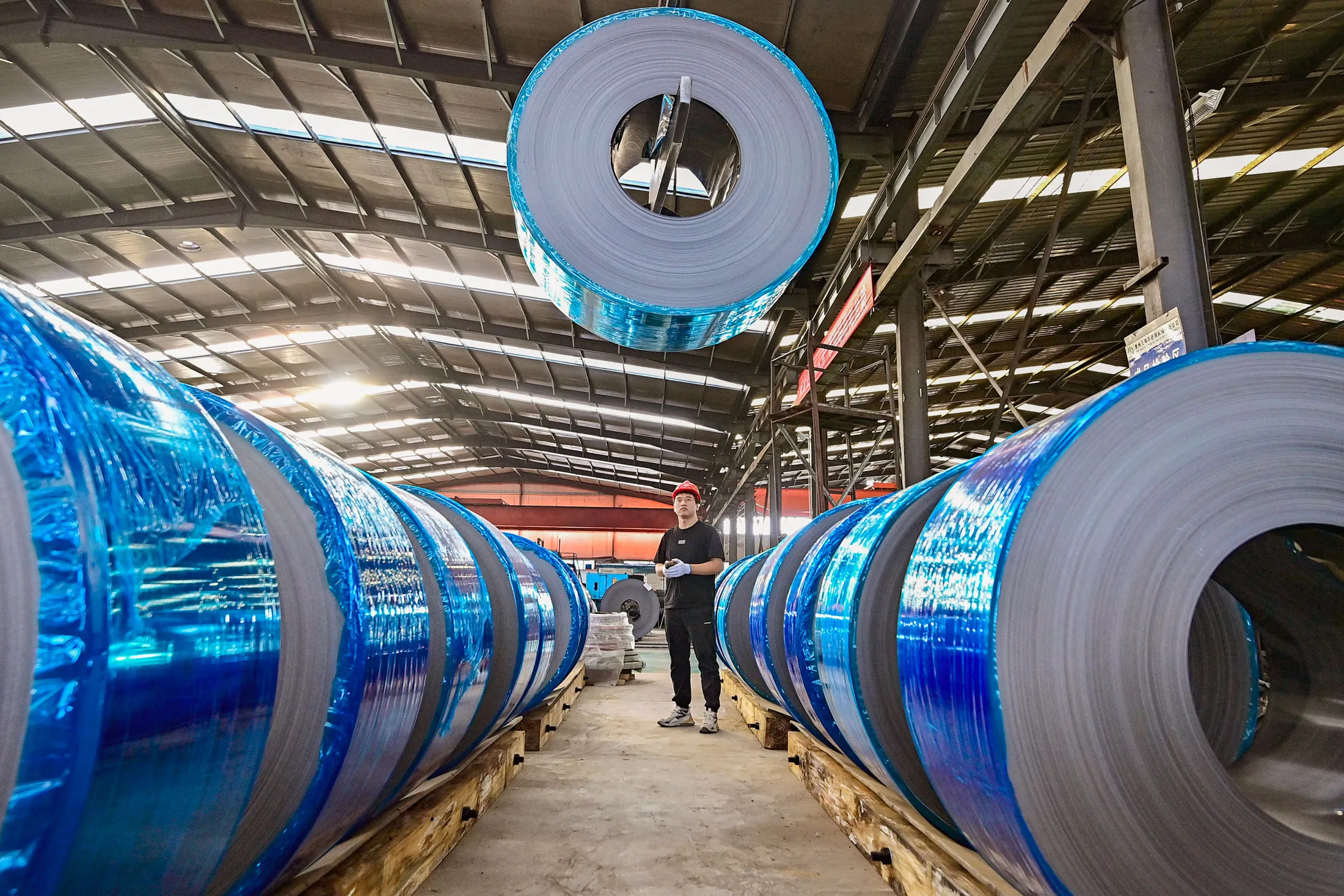 A worker moves rolled steel at a plant Qingzhou, China.