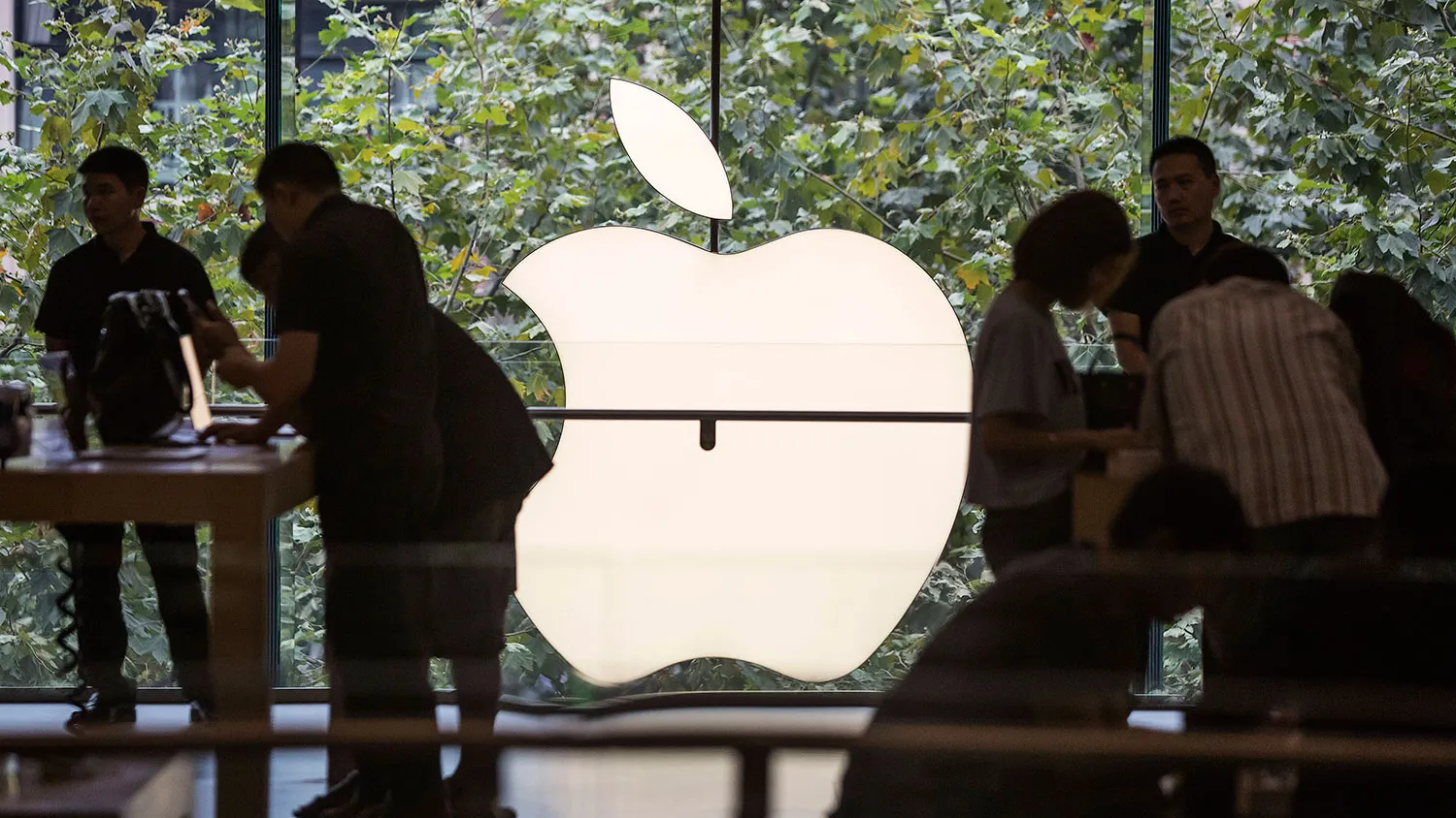 Customers look at products as an Apple Inc. logo is illuminated at a shopping mall in Shanghai on Sept. 25, 2015.
