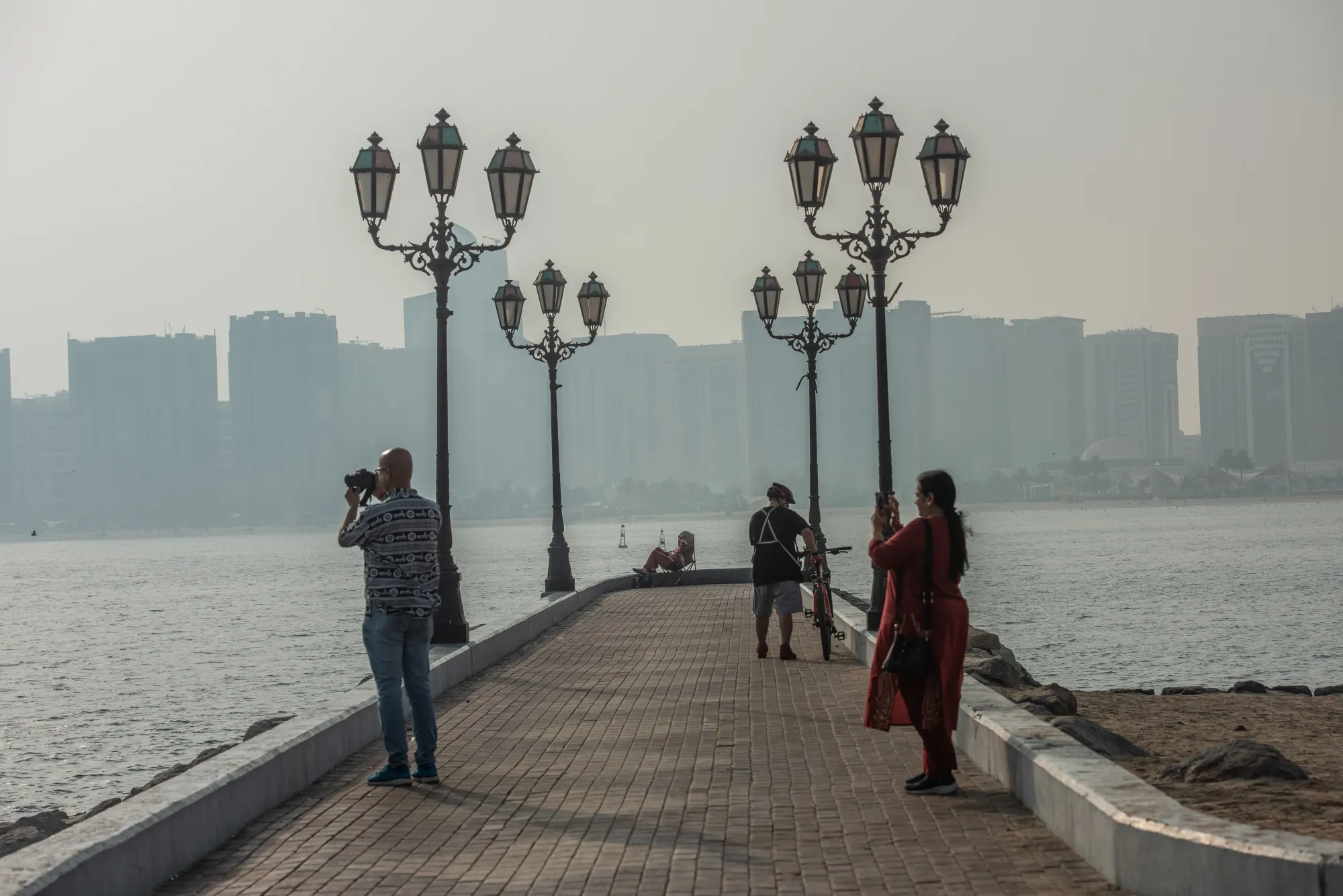 Tourists take photographs at the Corniche waterfront promenade in Abu Dhabi.