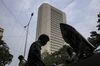 Pedestrians walk under power cables near the Reserve Bank of India (RBI) headquarter building in Mumbai, India, on Monday, Oct. 12, 2020. India’s financial capital saw its biggest power outage in decades because of a grid failure, disrupting transport networks and hitting trading volume in equities and bond markets.