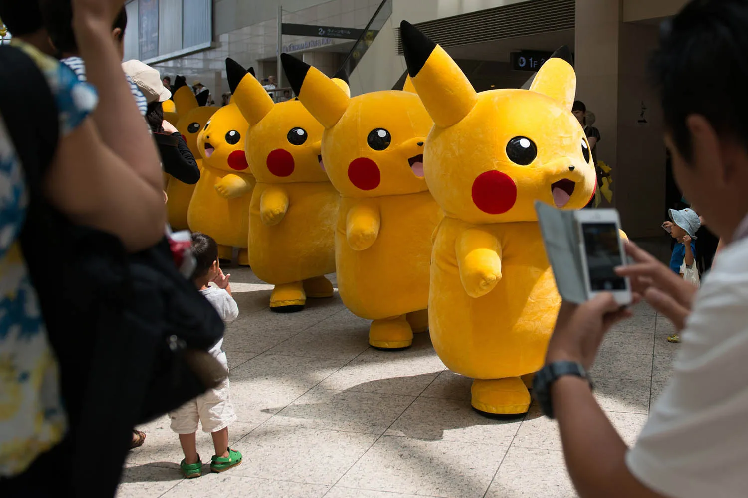 People take photographs of performers dressed as Pikachu, a character from Nintendo's Pokemon game. Pokemon Go will be available on Apple Inc. iPhones and Google Android devices.
