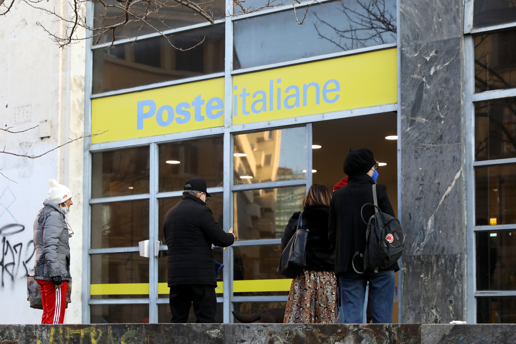 Customers queue outside a Poste Italiane SpA branch in Rome, Italy.