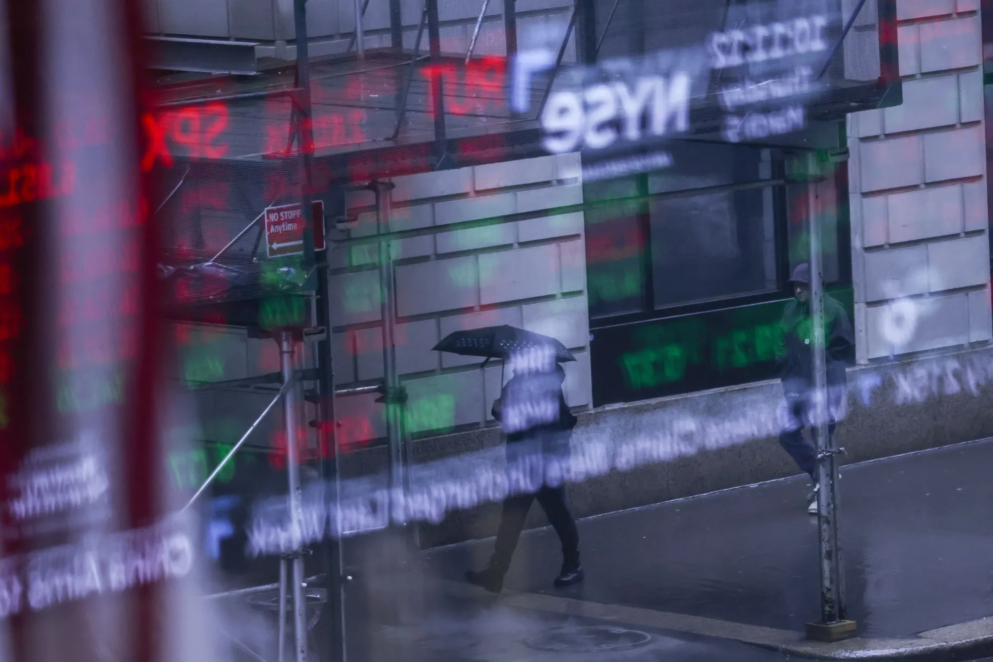 A pedestrian holding an umbrella outside of the New York Stock Exchange (NYSE) in New York.
