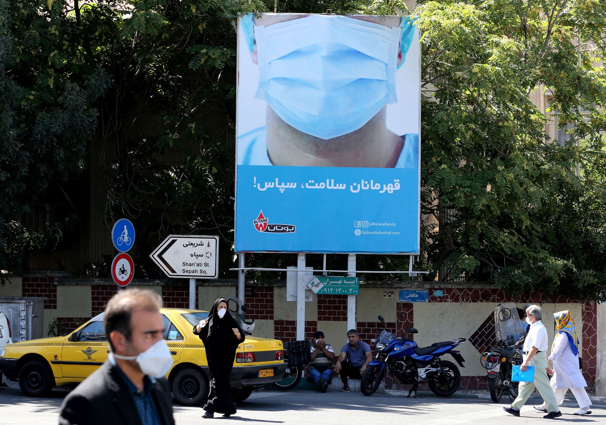 Iranian, wearing protective face masks&nbsp;walk under a billboard thanking first responders in&nbsp;Tehran on July 22.