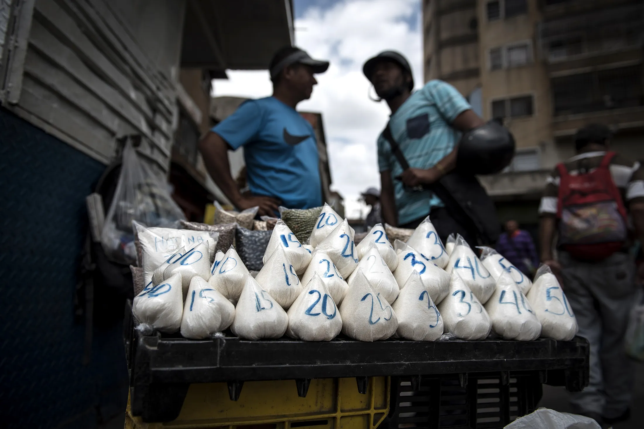 A street vendor sells bagged portions of sugar, salt and beans at a stand in the Petare slum of Caracas, on April 14, 2018.