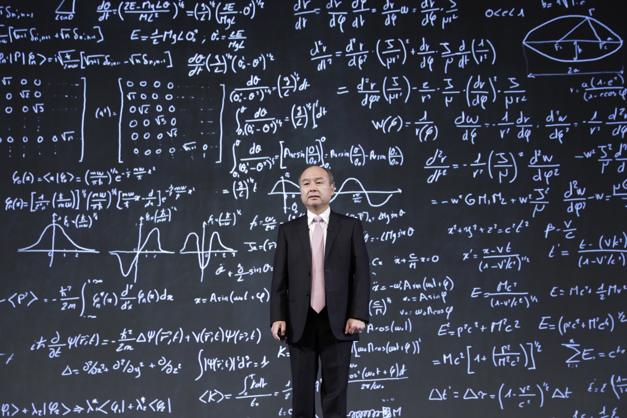 Masayoshi Son stands in front of the screen showing equations during a news conference in Feb. 2019.